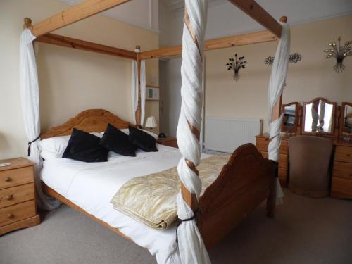 1 dormitorio con cama con dosel, sábanas y almohadas blancas en Maryland Bed and Breakfast, en Bridlington