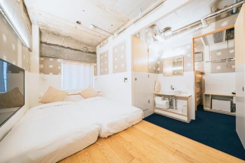 a bedroom with a large white bed and a kitchen at Of Hotel in Sendai