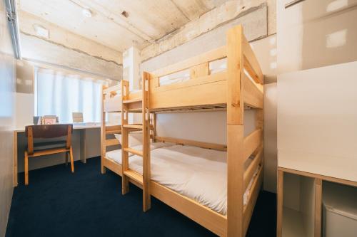 a bunk bed in a room with a desk and a chair at Of Hotel in Sendai