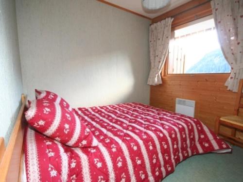 une chambre avec un lit avec une couverture rouge et une fenêtre dans l'établissement Appartement Châtel 5 pers, Terrasse, Animal admis - FR-1-676-77, à Châtel