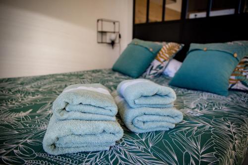 une pile de serviettes posée sur un lit dans l'établissement STUDIO ÉLÉGANT & MODERNE - ENTRE LAVANDE ET GORGES DU VERDON, à Gréoux-les-Bains