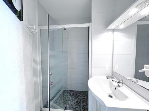 une salle de bain blanche avec une douche et un lavabo dans l'établissement Appartement 2P cabine, face plage, clim, parking privatif - FR-1-338-609, à Sète