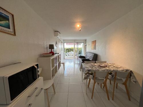 Il comprend une cuisine et un salon avec une table et un four micro-ondes. dans l'établissement Appartement 2P cabine, face plage, clim, parking privatif - FR-1-338-609, à Sète