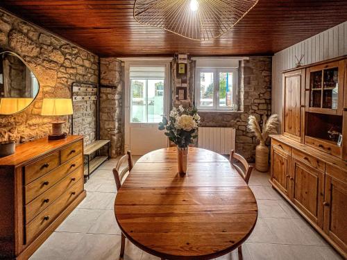 une salle à manger avec une table en bois et des fleurs. dans l'établissement Étel - Maison rénovée 3 pièces cosy avec WiFi - FR-1-479-224, à Étel