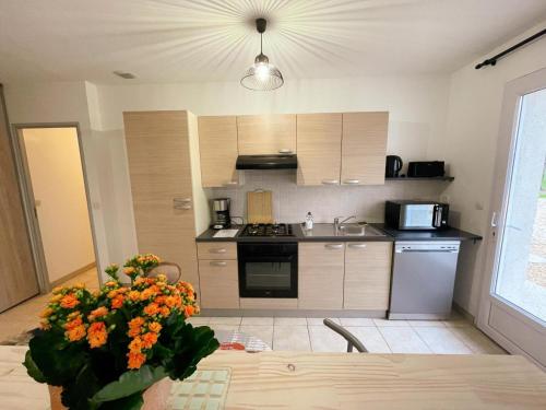 a kitchen with a table with a vase of flowers at Gîte de plain-pied en Touraine avec grand jardin et parking - FR-1-381-613 in Courcelles-de-Touraine