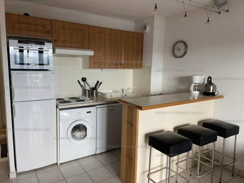 une cuisine avec un lave-linge et un comptoir avec des tabourets dans l'établissement Appartement T3 avec garage, proche des pistes, 6 couchages - FR-1-295-205, aux Angles