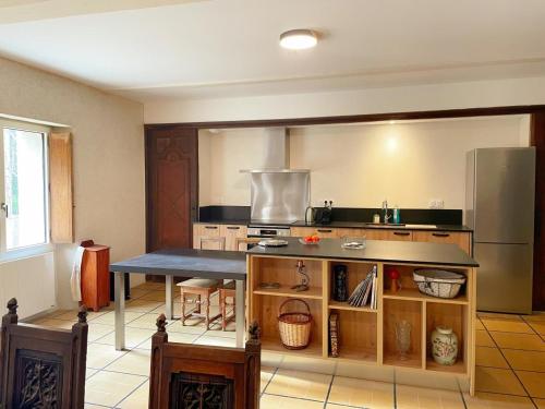 une cuisine avec une table et un réfrigérateur dans l'établissement Le Moulin de Ronsard : Demeure spacieuse, jardin et vue sur le Loir - 8 personnes - FR-1-491-459, à Couture-sur-Loir