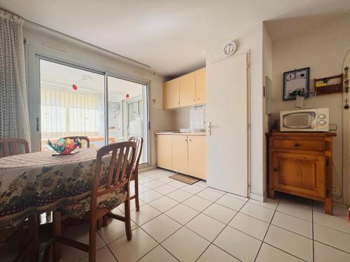 - une cuisine et une salle à manger avec une table et un four micro-ondes dans l'établissement Appartement T2 à Argelès-sur-Mer avec loggia, 4 couchages et piscine - FR-1-309-499, à Argelès-sur-Mer