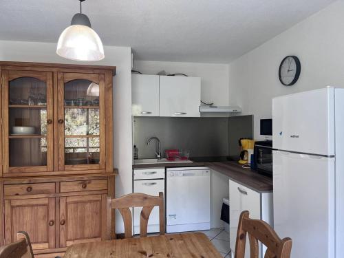 une cuisine avec une table et un réfrigérateur blanc dans l'établissement Chalet à Cauterets avec Parking, 2 Chambres - FR-1-812-134, à Cauterets