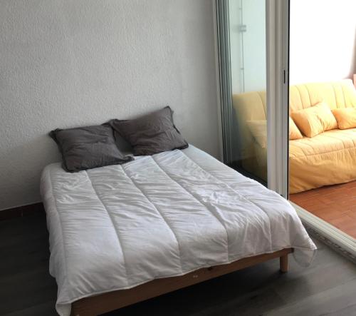un lit avec des draps blancs et des oreillers dans une chambre dans l'établissement Studio 0233, Port Camargue, Piscine, WiFi, Parking, 2 personnes, au Grau-du-Roi