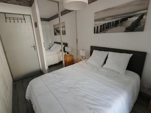une chambre avec un grand lit blanc et un miroir dans l'établissement Appartement moderne 2 chambres, proche plage et parking privatif - FR-1-732-104, à Argelès-sur-Mer