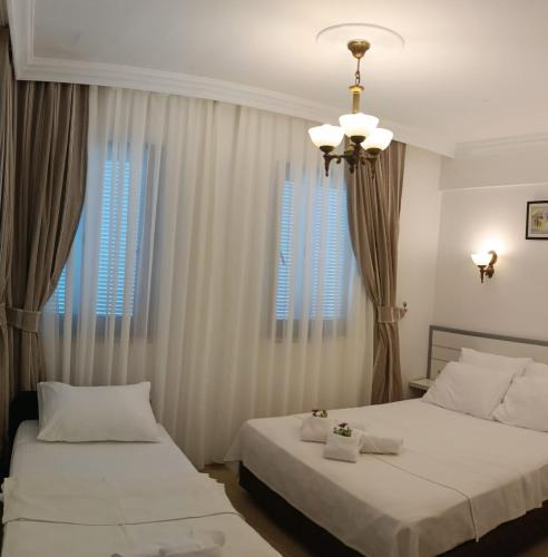 two beds in a bedroom with curtains and a chandelier at Bozcaada Su otel in Bozcaada