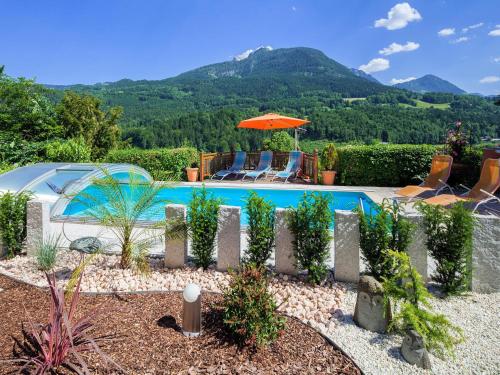 a swimming pool with chairs and an umbrella at Ferienwohnungen Scheifler in Berchtesgaden