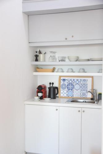 a kitchen counter with a sink and white cabinets at Caldera St G in Santorini