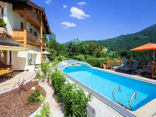 ein Pool neben einem Gebäude mit einem Berg in der Unterkunft Ferienwohnungen Scheifler in Berchtesgaden