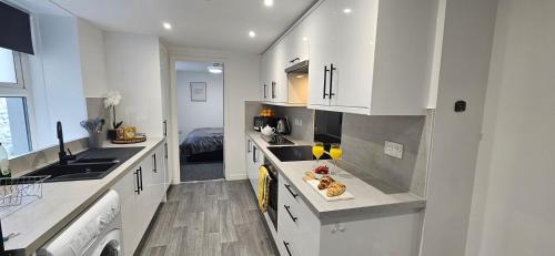 a kitchen with white cabinets and a sink at Modern, Spacious, Central 2-Bed Plymouth Apartment in Plymouth