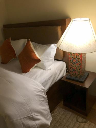 a bedroom with a bed with a lamp on a table at Zenith Apartments Thamel - Makalu 1BHK Apartment in Kathmandu