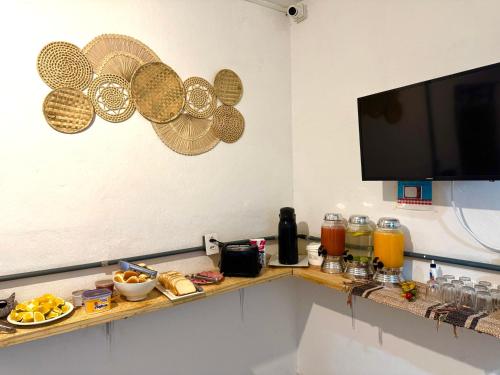 a room with a counter with food and a flat screen tv at Pinheiros Hostel & Food in Sao Paulo
