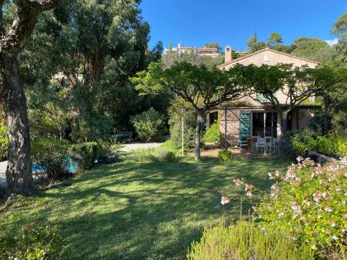 une maison avec une cour ornée d'arbres et de fleurs dans l'établissement Les Arbousiers - villa climatisée avec piscine, au calme, à La Londe-les-Maures