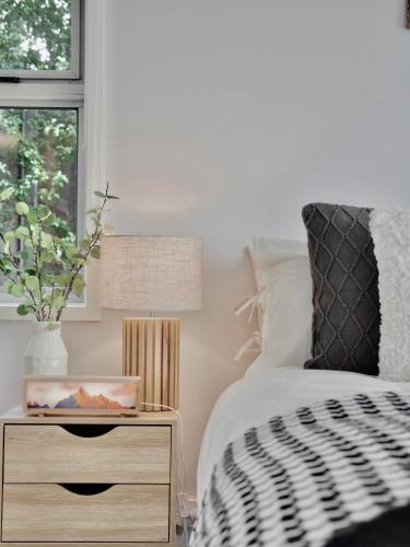 a bedroom with a bed and a nightstand with a lamp at Modern holiday home in Hobart - Stunning Mountain & Water views in Rosetta
