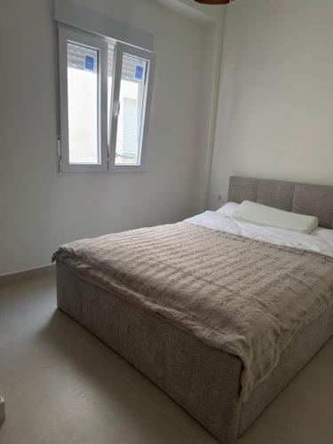 Bett in einem weißen Zimmer mit 2 Fenstern in der Unterkunft Cala LaMata Apartment in La Mata
