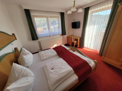 a bedroom with a white bed with a red blanket at Komfort Appartement Royal Windberger in Schladming