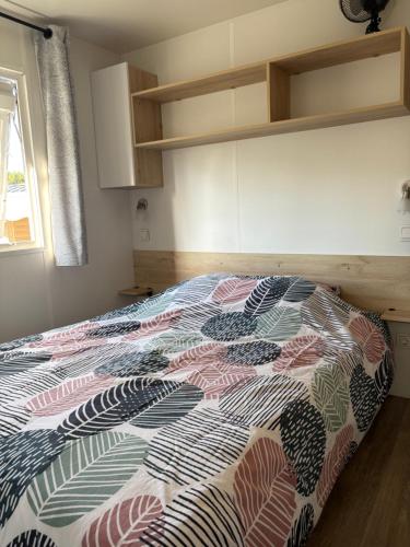 une chambre avec un lit avec une couette colorée dans l'établissement Camping Les Viviers chez So Claouey, à Lège-Cap-Ferret