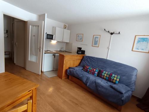 un salon avec un canapé bleu et une cuisine dans l'établissement Appartement skis aux pieds 6 pers, balcon, animaux admis - FR-1-445-99, à Montgenèvre