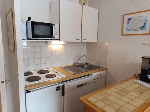 une cuisine avec une cuisinière, un évier et un micro-ondes dans l'établissement Montgenèvre - Appartement sur les pistes 4-6 pers., balcon sud-ouest, animaux acceptés - FR-1-445-107, à Montgenèvre
