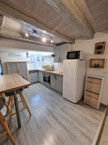 a large kitchen with a table and a refrigerator at Magnifique F2 du bien être in Besançon