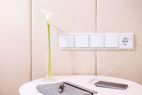 a white table with a vase with a flower on it at NH Collection Wien Zentrum in Vienna