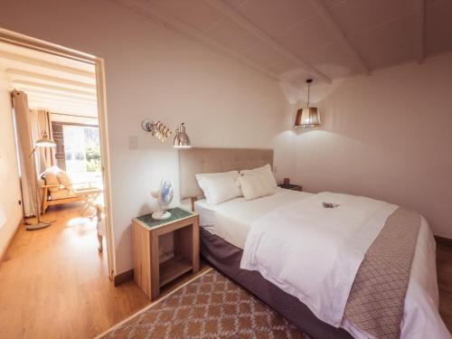 a bedroom with a large white bed and a table at Fiddler's Green in Magoebaskloof