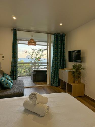 a bedroom with a bed and a television and a balcony at Studio vue mer avec piscine - Le Diamant in Le Diamant