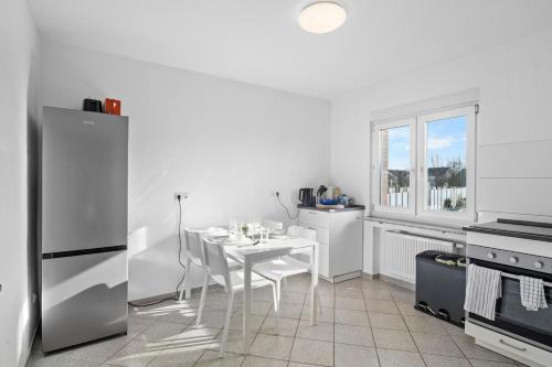 a kitchen with a white table and a white refrigerator at BA01 Moderne Wohnung in Flörsheim in Flörsheim