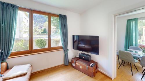 sala de estar con TV de pantalla plana junto a una ventana en 4,5 Zimmer Wohnung - Zentral - Solution-Grischun, en Chur