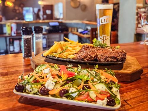 two plates of food on a wooden table with a drink at Fiddler's Green in Magoebaskloof