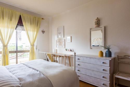 a bedroom with a bed and a dresser and a mirror at Bright Apartment 10min from 2 stunning Beaches in Olhos de Água