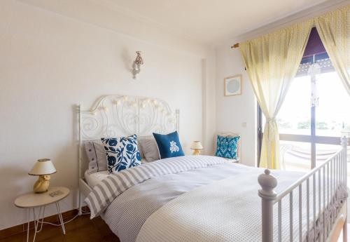 a bedroom with a white bed and a window at Bright Apartment 10min from 2 stunning Beaches in Olhos de Água