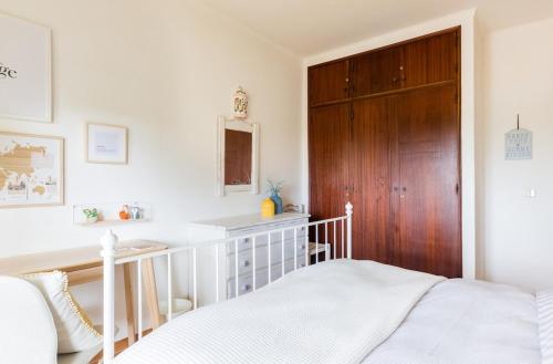 a bedroom with a bed and a wooden door at Bright Apartment 10min from 2 stunning Beaches in Olhos de Água