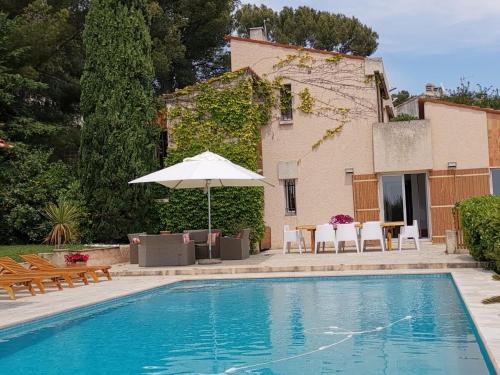une piscine avec un parasol et des chaises ainsi qu'une maison dans l'établissement Superbe villa vue et emplacement exceptionne, à Cassis