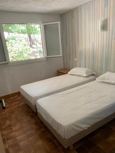 deux lits dans une chambre avec une fenêtre dans l'établissement Résidence U LATONU, à Porto-Vecchio