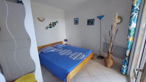 - une chambre avec un lit bleu dans l'établissement 2 pièces accès direct plage, à Sainte-Lucie de Porto-Vecchio