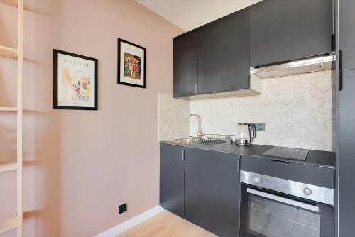une cuisine avec des armoires noires et un comptoir dans l'établissement Studio refait à neuf avec balcon et vue sur la Seine - bail mobilité, à Paris