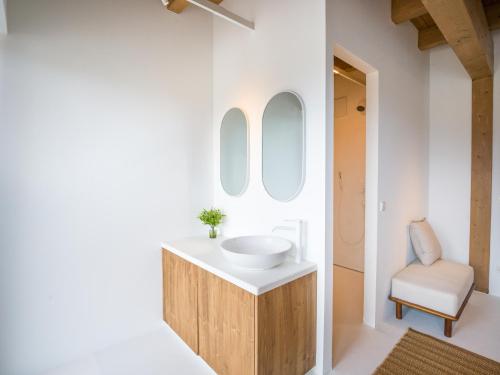 a bathroom with a white sink and a chair at PENTHOUSE N`4 - Stylish Apartment with Rooftop Whirlpool Access in Tyrol, presented by AlpenLuxus in Kramsach