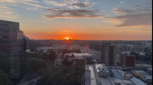 a city skyline with the sun setting in the distance at Sydney Private Home I in Bankstown