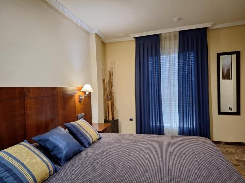 a bedroom with a large bed with blue pillows at Cazorla LIVE in Cazorla