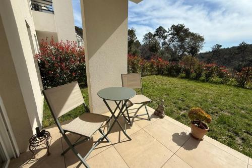 un patio con mesa, sillas y un campo de flores en Cosy flat - Garden - Swimming pool, en Valbonne