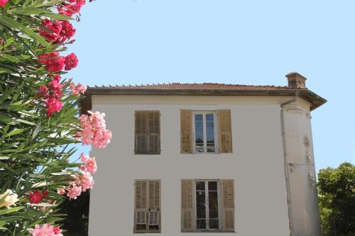 une maison blanche avec des fleurs roses devant elle dans l'établissement Explore Nice from our cozy & quiet 2BR aptparking, à Nice