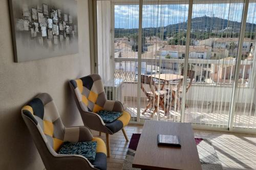 une chambre avec des chaises, une table et un balcon dans l'établissement Naturiste Cap d'Agde Port Soleil 589, au Cap d'Agde