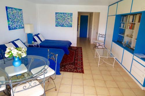 - un salon avec un lit bleu et une table en verre dans l'établissement MAGNIFICENT SEAFRONT Studio, à Mandelieu-la-Napoule